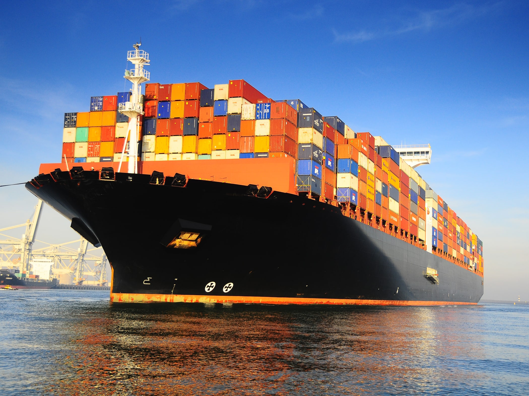 https://fastdeliveryshippingagency.com/wp-content/uploads/2021/02/orange-black-loaded-container-ship-harbour.jpg